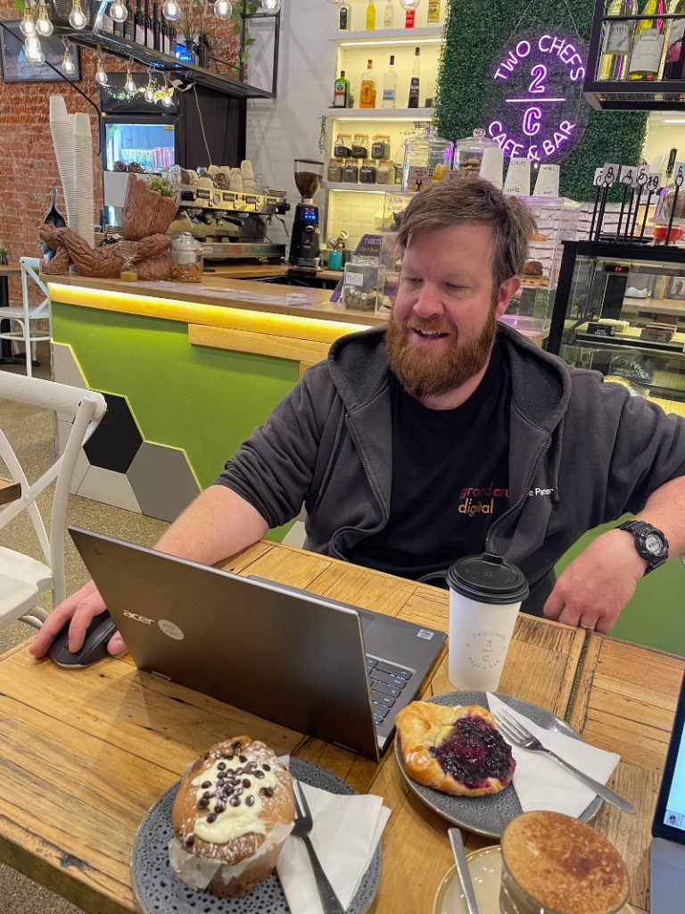 Morgan with a laptop 2 coffees and 2 sweet treats at 2 Chefs Cafe & Bar